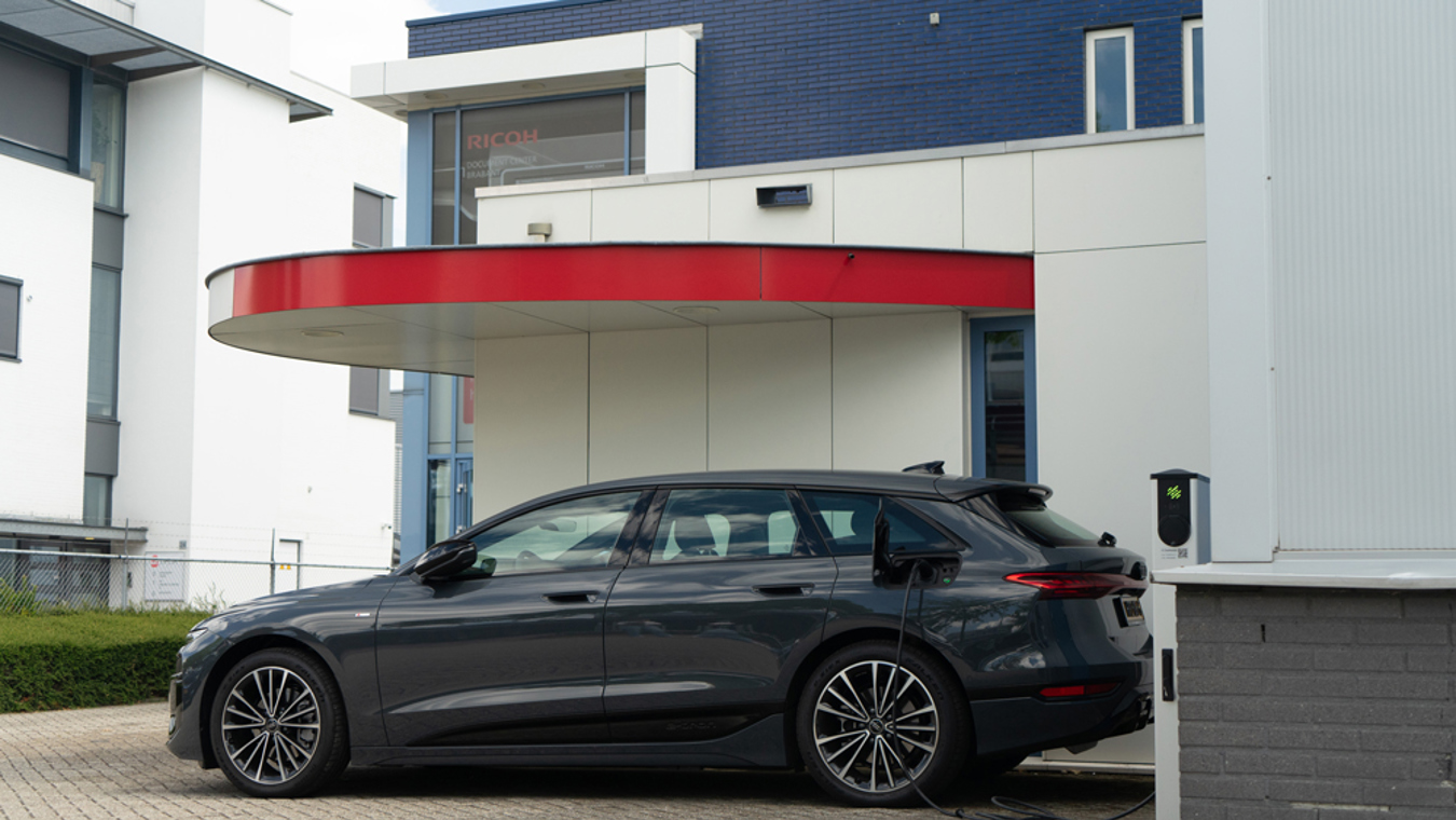 Elektrische auto bij een Lumosa TRACK laadpaal op het parkeerterrein van Ricoh Document Center Brabant in Eindhoven.